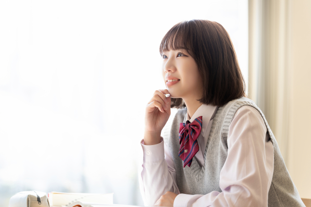 顎に手を当てて考える制服を着た女の子