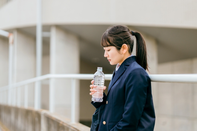 俯きながらペットボトルを持っている女子生徒