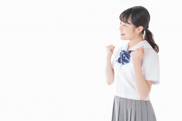 両手を胸の横で握っている女の子
