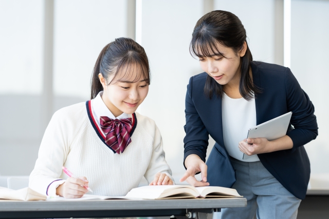 女性に教えてもらっている女子生徒