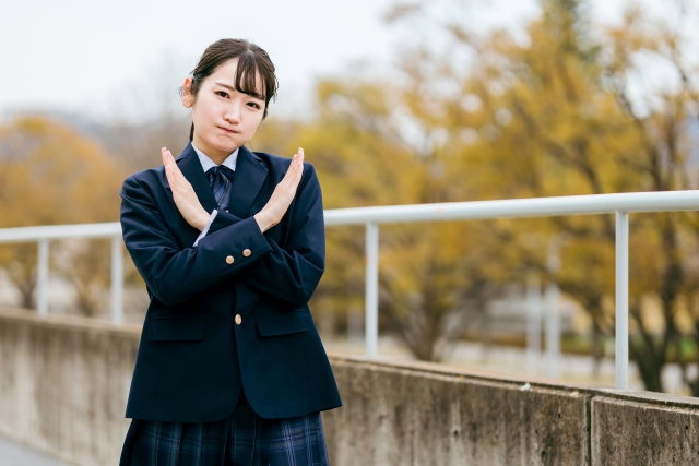 両手で×を作っている女子生徒