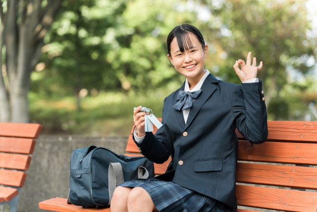 片手に単語帳を持ちもう片方の手でOKサインを作っている女子生徒