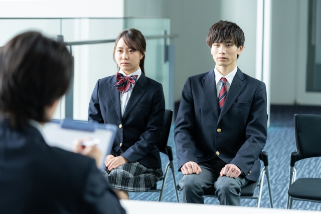 面接を受けている制服を着た男女の学生