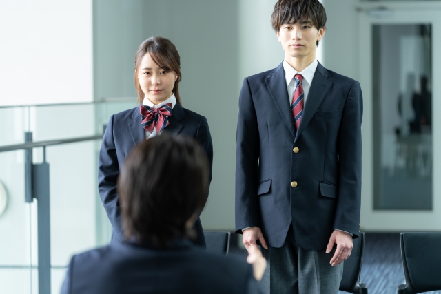 面接で椅子の前に立っている制服を着ている男女