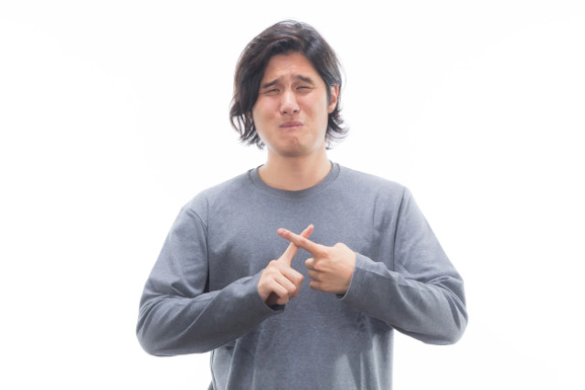 胸の前でバツ印を作っている男性