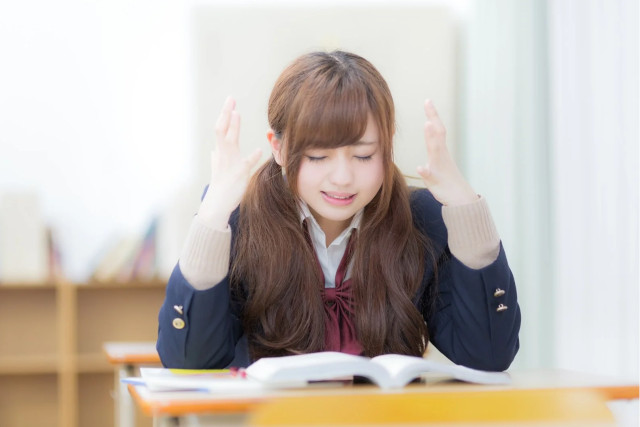 ノートを開いて頭を抱える女子学生