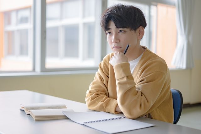 勉強しながら頬杖をついて悩む男の子